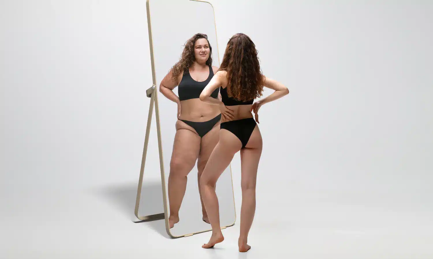 Woman looking in the mirror after she was able to lose weight without exercise.