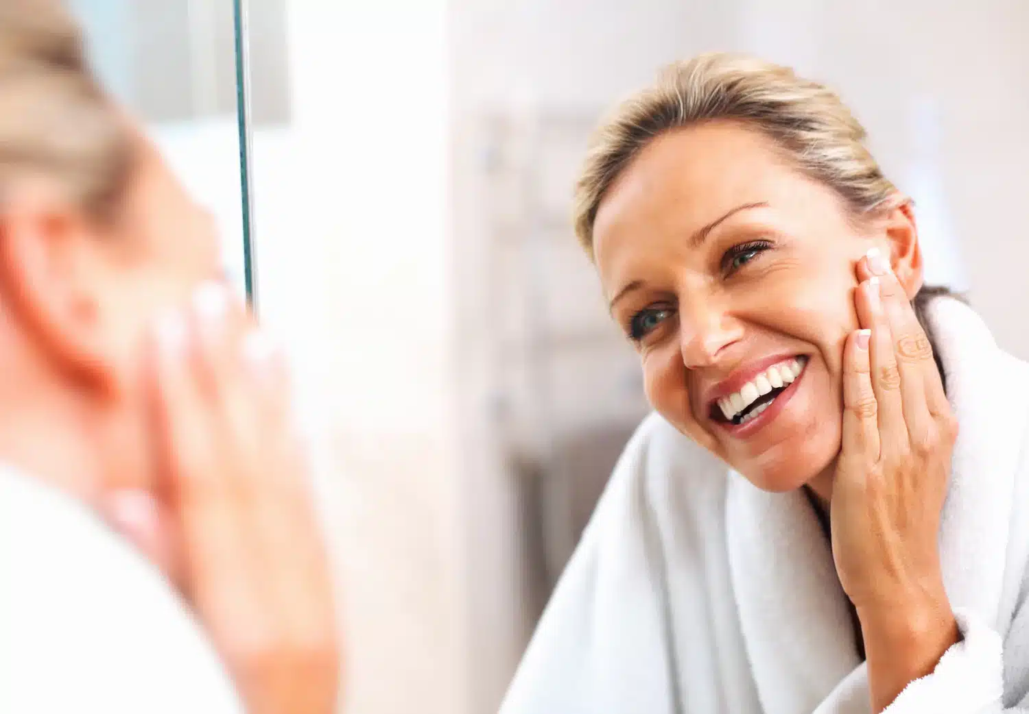 Happy woman looking at her skin in the mirror.